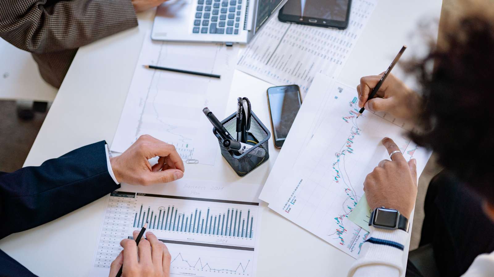 Dos personas analizando gráficos y datos financieros sobre un escritorio
