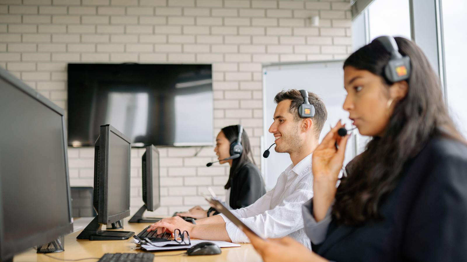 Equipo de soporte con headsets monitoreando pantallas en un centro de atención TI